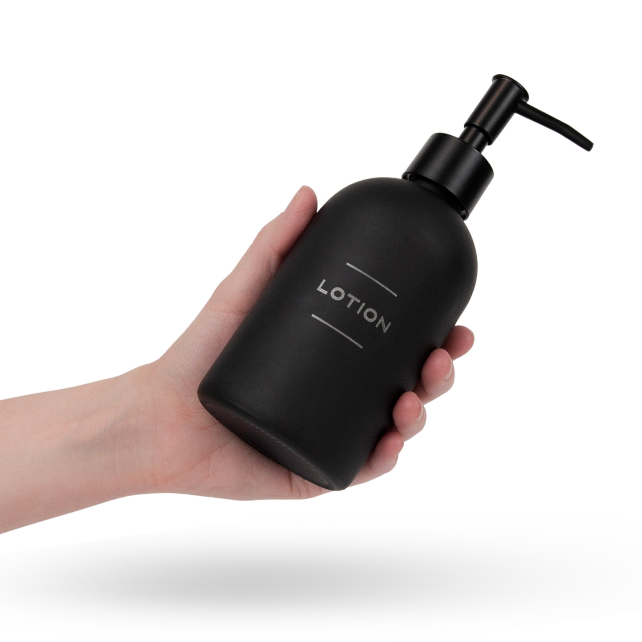 A hand holds a matte black glass lotion dispenser bottle with laser engraved lettering